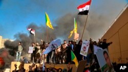 Protesters burn property in front of the U.S. embassy compound, in Baghdad, Iraq, Tuesday, Dec. 31, 2019. Dozens of angry Iraqi Shiite militia supporters broke into the U.S. Embassy compound in Baghdad on Tuesday. (AP Photo/Khalid Mohammed)