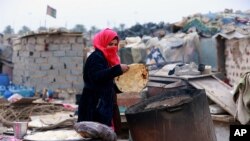 2018年2月12日悠姆薩蘭姆(Umm Salem)在她的屋子前面烤面包。她住在伊拉克巴格達外流離失所的人的營地