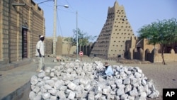 In this May 1, 2012 photo, men work alongside one of Timbuktu's historic mud mosques in Mali. 