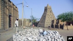 In this May 1, 2012 photo, men work alongside one of Timburktu's historic mud mosques, in Mali. 