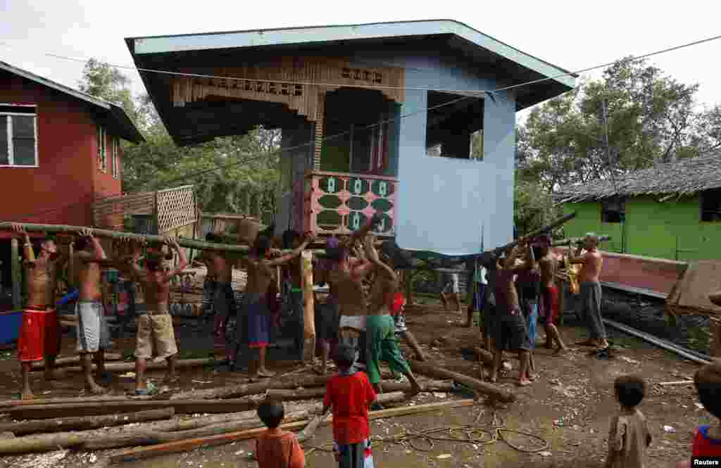 Residents lift a house damaged by Typhoon Rammasun in Batangas city, south of Manila, July 17, 2014.