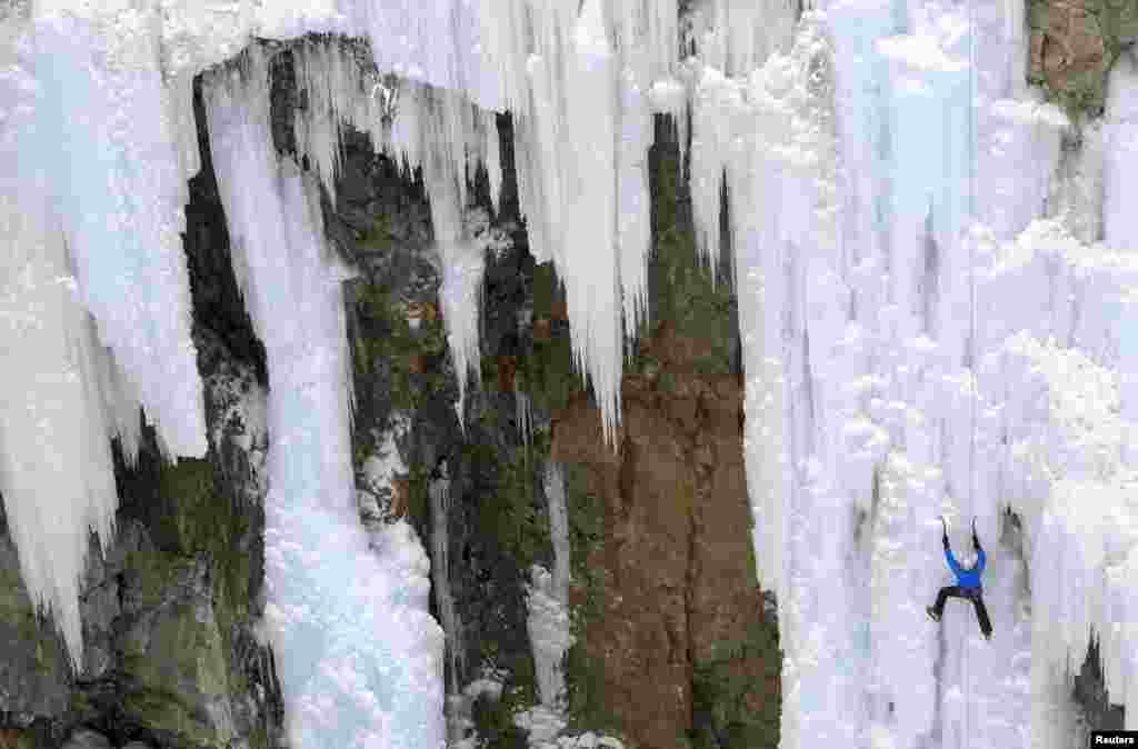 A man climbs up an artificially made wall of ice near the Swiss mountain resort of Pontresina, Switzerland. 