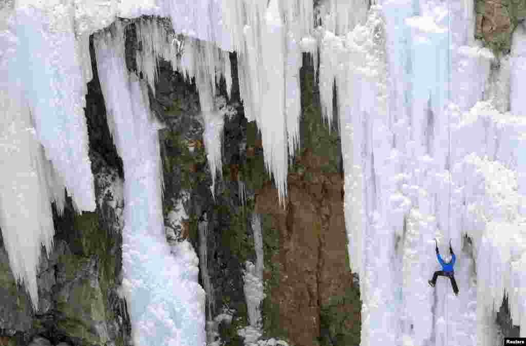 A man climbs up an artificially made wall of ice near the Swiss mountain resort of Pontresina, Switzerland.