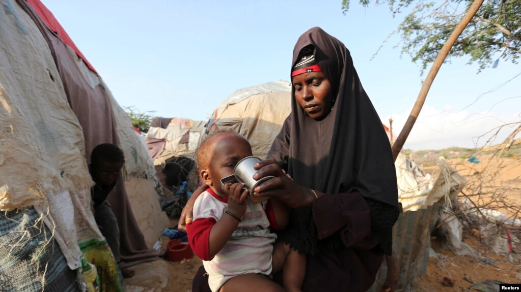 FILE - Rukia Nur feeds her child outside her makeshift dwelling after fleeing famine in the Marka Lower Shebbele regions to the capital Mogadishu.