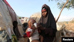 FILE - Rukia Nur feeds her child outside her makeshift dwelling after fleeing famine in the Marka Lower Shebbele regions to the capital Mogadishu.