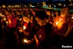 FILE - Members of the community reflect as they hold candles during a commemoration and candlelight vigil on the campus of Virginia Tech in Blacksburg, Virginia, April 16, 2012, five years after a mentally ill student gunned down 32 people at the university.