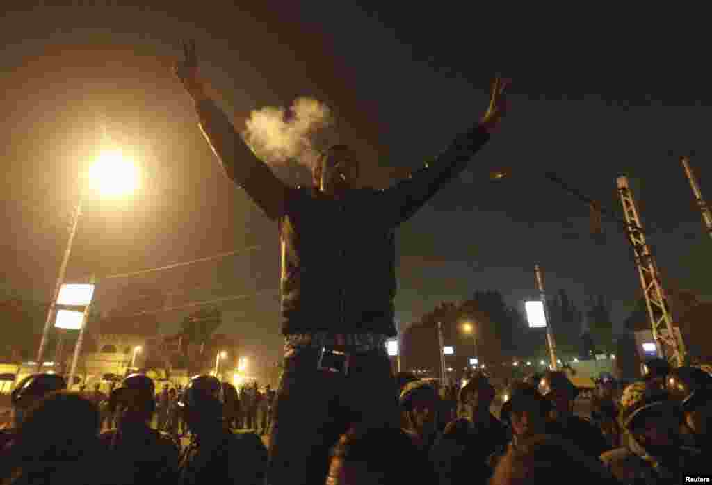 An anti-Morsi protester smokes a cigarette and and gestures in front of members of the Republican Guard blocking a road to the presidential palace in Cairo, Egypt, December 6, 2012.