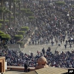 Pro-government demonstrators, below, clash with anti-government demonstrators, above, as an Egyptian Army soldier on the rooftop of the Egyptian Museum observes the scene in Tahrir square, in Cairo, February 02, 2011.