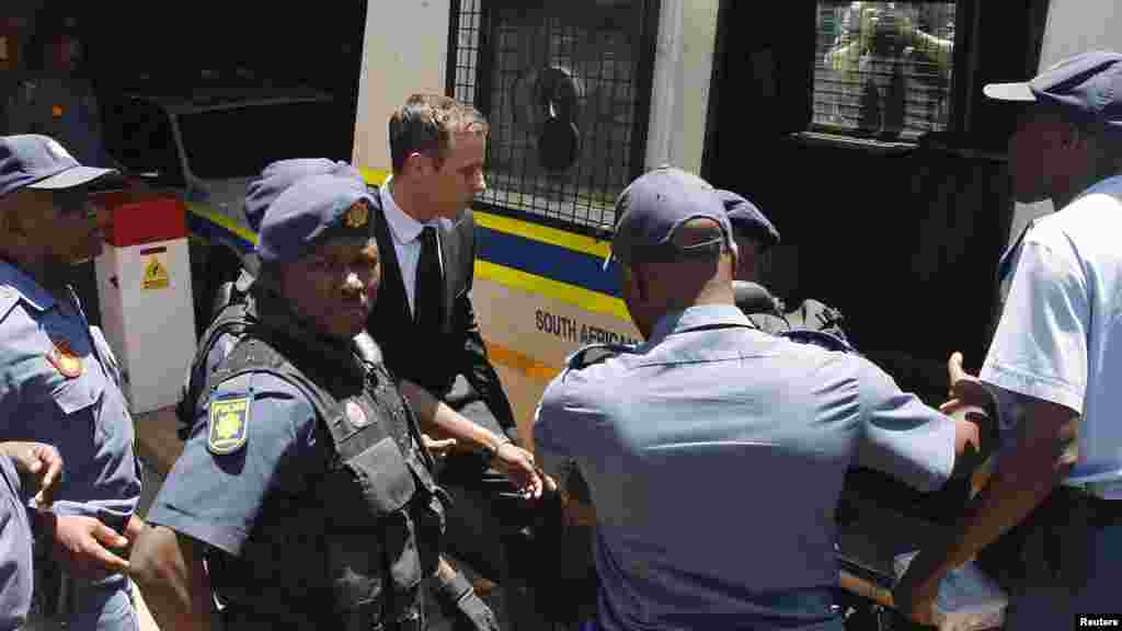 South African Olympic and Paralympic sprinter Oscar Pistorius, center, enters a police van after his sentencing at the North Gauteng High Court in Pretoria, Oct. 21, 2014. 