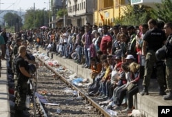 Police officers secure the railway tracks before a train that would take the migrants towards Serbia enters the railway station in the southern Macedonian town of Gevgelija, Aug. 23, 2015.