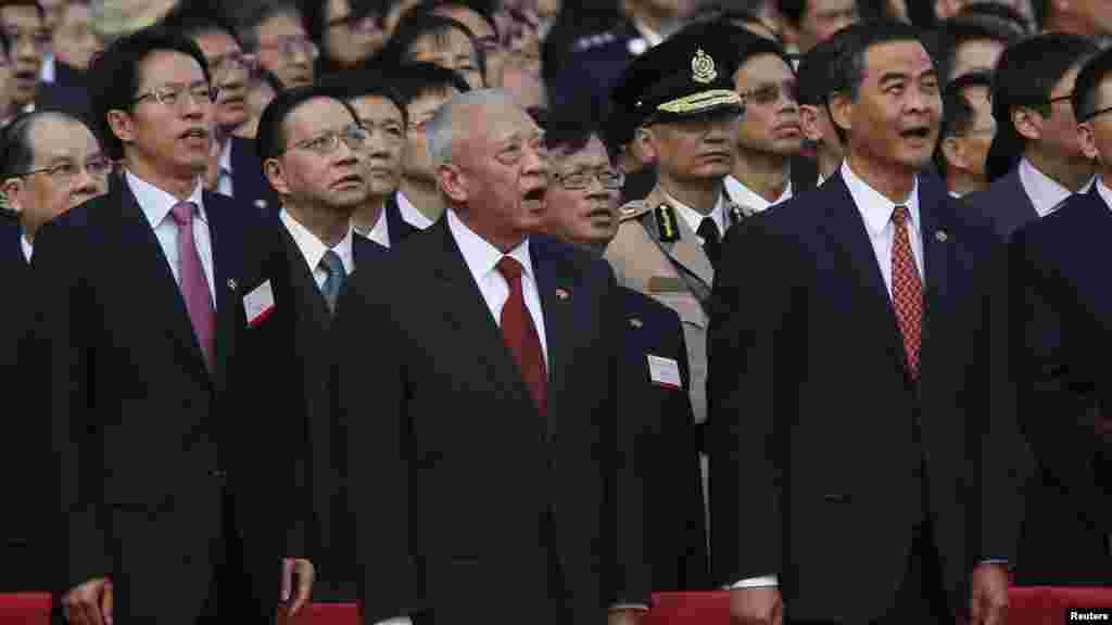 (From left) Zhang Xiaoming, director of the Liaison Office of the Central People's Government in Hong Kong, former Hong Kong Chief Executive Tung Chee-hwa, and Hong Kong Chief Executive Leung Chun-ying sing the national anthem during a flag-raising ceremo