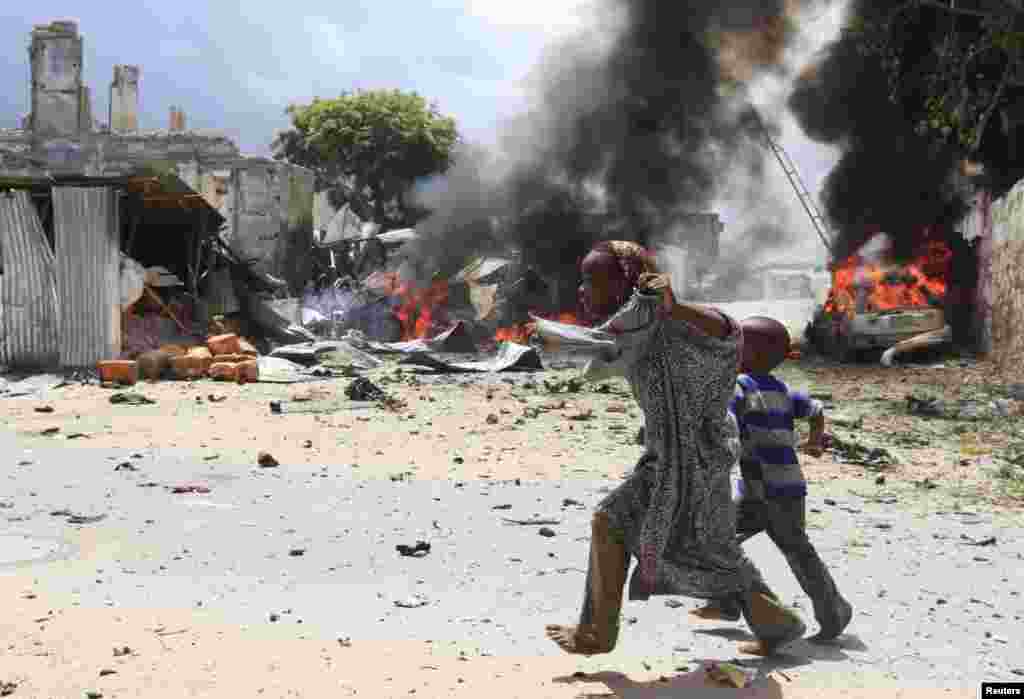 A Somali girl and her brother run to safety near the scene of a blast in Mogadishu, April 14, 2013.