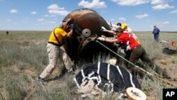 Tripulantes de apoyo ayudaron a los tres a salir de la cápsula, que estaba chamuscada tras su descenso a través de la atmósfera y a recostarse en reposeras para un chequeo rápido.