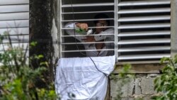 Yunior García, disidente cubano, saluda desde su ventana mientras permanece bloqueado por simpatizantes del gobierno, el domingo 14 de noviembre de 2021.