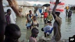 FILE - Displaced South Sudanese walk through flood waters to move around a makeshift camp. 