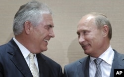 FILE - Russian Prime Minister Vladimir Putin, right, and Rex Tillerson, ExxonMobil's chief executive smile during a signing ceremony in the Black Sea resort of Sochi, Russia, Aug. 30, 2011.