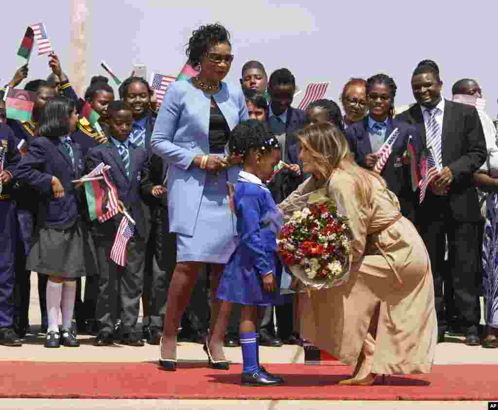 First lady Melania Trump is greeted by Malawi first lady Gertrude Maseko and a flower girl as she arrives at Lilongwe International Airport, in Lumbadzi, Malawi, Oct. 4, 2018. 