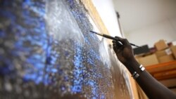 Senegalese artist Omar Ba paints on a canvas hanging from the wall of his studio in Bambilor, Senegal on March 12, 2021. REUTERS/ Cooper Inveen