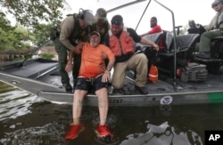 John Paul Klotz, 80, is pulled on a boat by U.S. Border Patrol Agents Steven Blackburn, left, Ramiro Rodriguez, top center, and Juan Flores during a search-and-rescue operation in a neighborhood inundated by floodwaters from Tropical Storm Harvey in Houston, Texas, Aug. 30, 2017.
