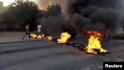 People walk past burning objects lying on the streets of Kartoum, Sudan, amid reports of a coup, Oct. 25, 2021, in this still image from video obtained via social media.