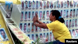 Seorang perempuan menangis di depan barisan foto orang hilang di kota Medellin, Kolombia. (Foto: Dok)