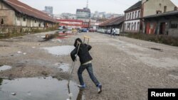 A migrant plays with crutches in front of a derelict customs warehouse in Belgrade, Serbia, November 10, 2016.
