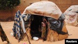 FILE - A girl stands outside a hut in Niger's capital, Niamey. In impoverished Niger, recurring and more intense drought "is absolutely punishing," a U.N. official says.
