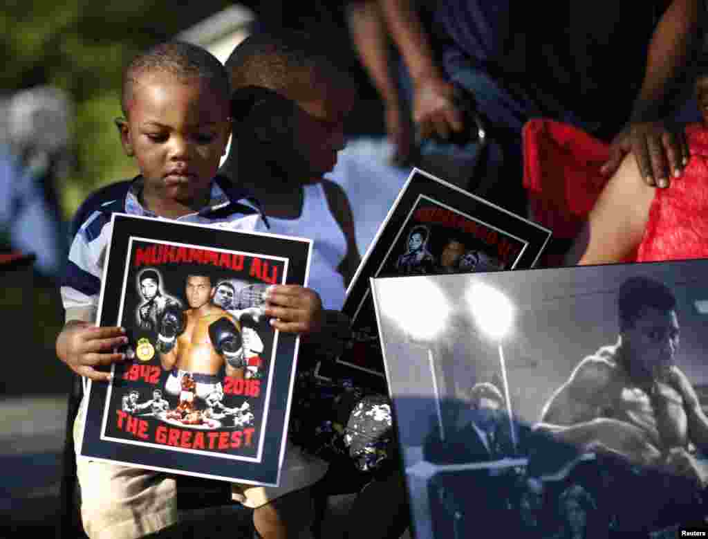 Brandon Liggons, 2, holds an image of Muhammad Ali during the funeral procession for the three-time heavyweight boxing champion in Louisville, Kentucky, U.S., June 10, 2016. REUTERS/Lucy Nicholson