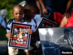 Brandon Liggons, 2, (L) holds an image of Muhammad Ali during the funeral procession for the three-time heavyweight boxing champion in Louisville, Kentucky, June 10, 2016.