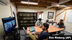 RunX CEO Ankur Dahiya, center, takes part in a video meeting with employees JD Palomino, top left, and Nitin Aggarwal, right, at a temporary office in San Francisco, Friday, Aug. 27, 2021. Technology companies like RunX that led the move into remote work early as the pandemic started, are facing a new difficulty as it calms down: how, when and even if they should bring their employees back to offices that have been made for teamwork. (AP Photo/Eric Risberg)