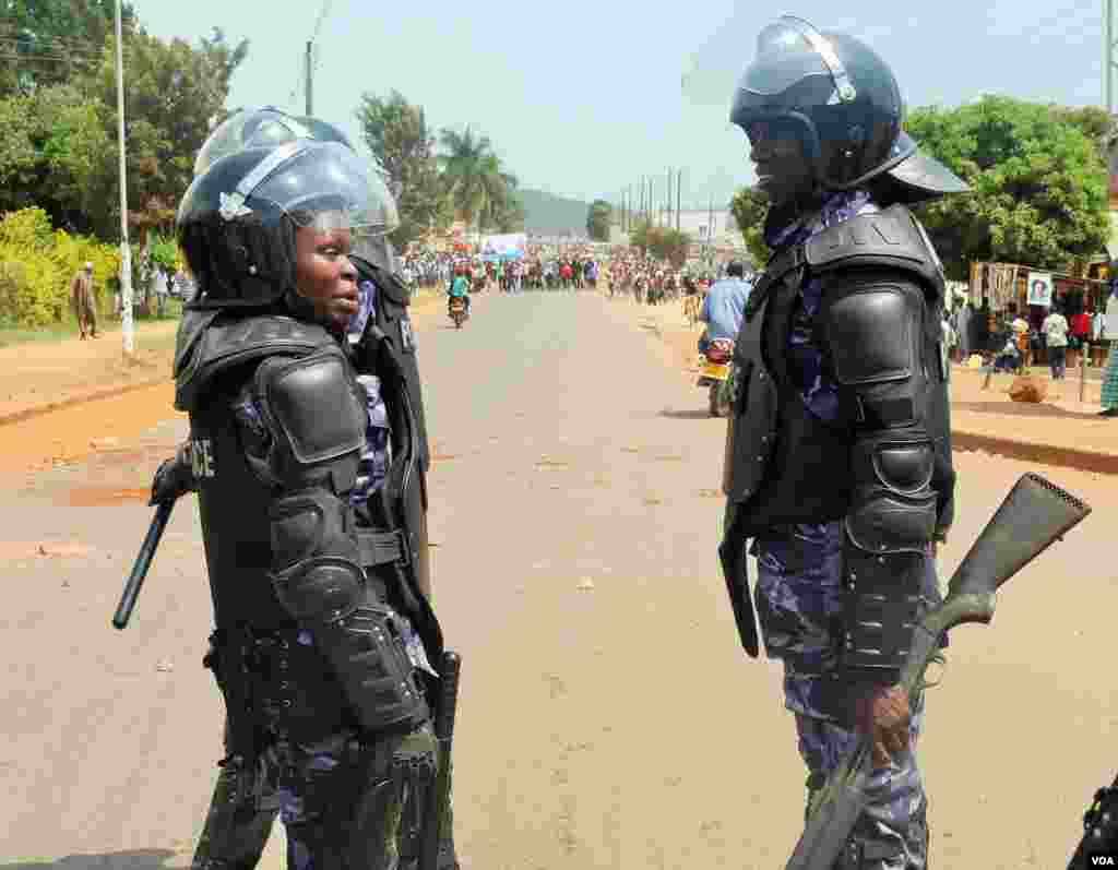 Two police officers in riot gear talk as the line of angry voters in Kampala advances. E. Paulat/VOA