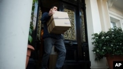 A removals worker carries a box out of the residential annex of the Iranian embassy in central London December 2, 2011.