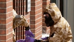 Specialist team members in military protective suits use a jar in the front doorway as they search the fenced-off John Baker House for homeless people on Rollestone Street in Salisbury, England, July 6, 2018. British police are scouring sections of Salisb