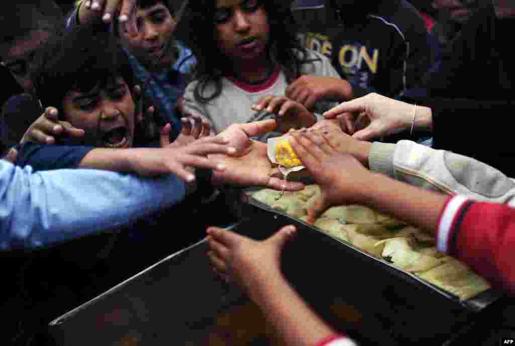 Syrian refugees try to grab food in a park, in Istanbul, Turkey. 