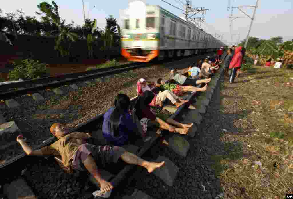July 13: Residents lie on railway tracks in Rawa Buaya in Indonesia's West Java province. The residents believe that the electrical energy from the tracks will cure them of various illnesses. REUTERS/Enny Nuraheni
