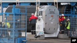 FILE - Harbour and Areva workers check a container carrying uranium oxide to make fuel pellets called MOX or mixed-oxide moment before being lifted onto the Pacific Egret cargo in Cherbourg harbor, western France, before heading for Japan, April 17, 2013. The Pacific Egret and Pacific Heron will take will take the 331 kilograms (730 pounds) of plutonium to the Savannah River Site, a U.S. government facility in South Carolina, under a pledge made by Japan in 2014.