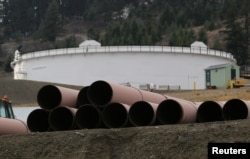 FILE - Replacement pipe is stored near crude oil storage tanks at Kinder Morgan's Trans Mountain pipeline terminal in Kamloops, British Columbia, Canada, Nov. 15, 2016.