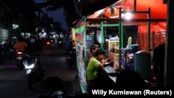 Orang-orang tengah menikmati makan malam di tenda jajanan kaki lima saat pelonggaran PPKM di tengah pandemi COVID-19, di Jakarta, 28 Juli 2021. (Foto: REUTERS/Willy Kurniawan)