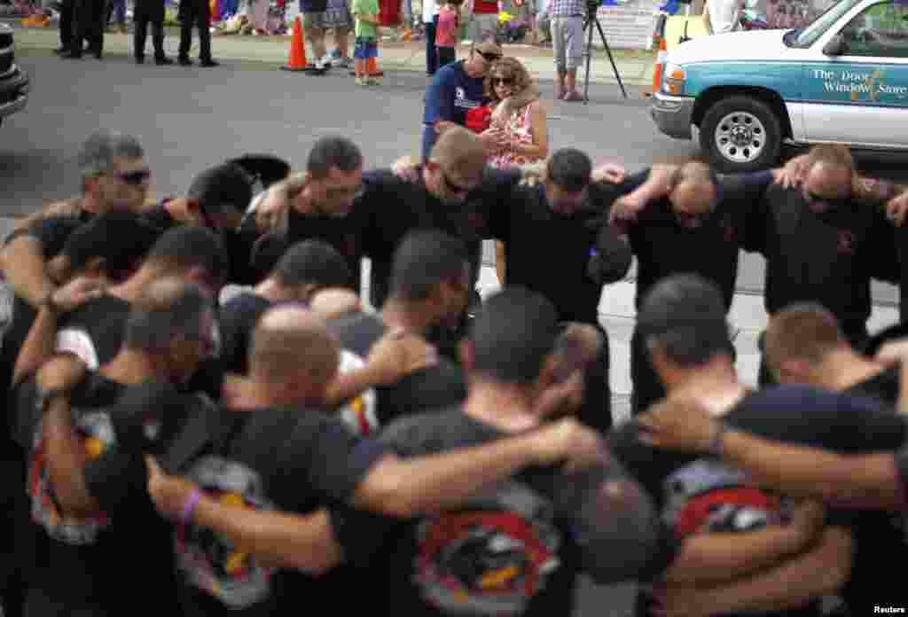 Joe and Anna Woyjeck, parents of fallen firefighter Kevin Woyjeck, hug as firefighters pray in front of a memorial dedicated to the 19 firefighters killed in the nearby wildfire in Prescott, Arizona, July 8, 2013. 