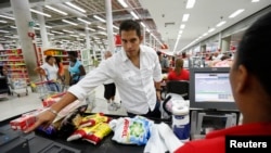 A customer puts his finger on a fingerprint scanner as part of the process to buy groceries at Bicentenario, a state-run supermarket, in Caracas, Venezuela, Sept. 25, 2014.