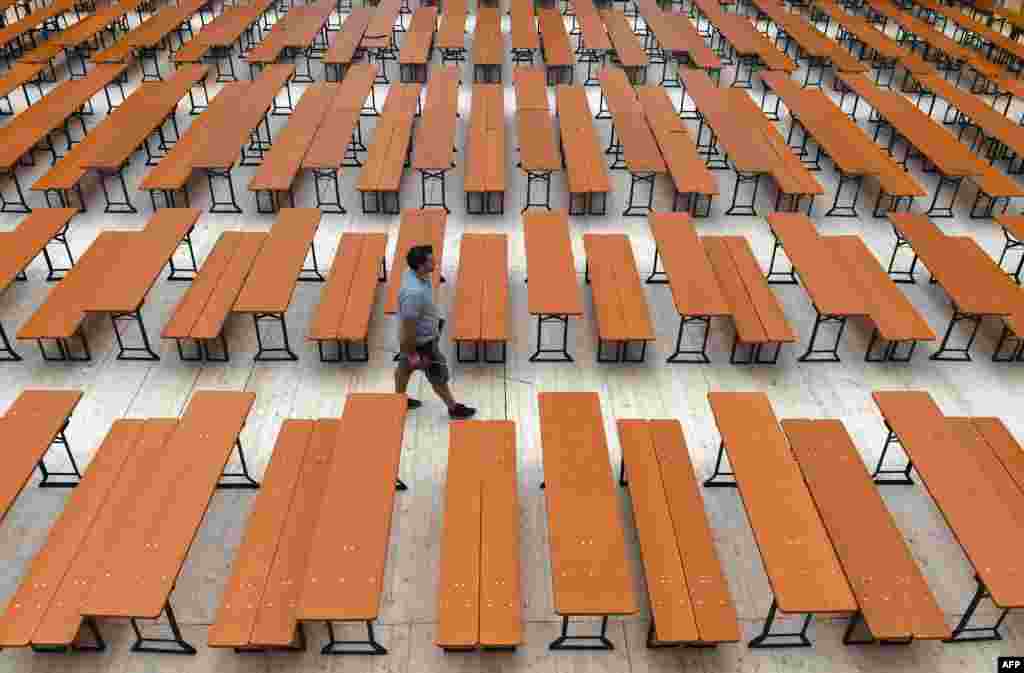 A man walks along empty benches in an Oktoberfest tent prior to the opening of the Oktoberfest beer festival at the Theresienwiese fairgrounds in Munich, southern Germany. The world&#39;s biggest beer festival opens on Sept. 17, 2016, and runs until Oct. 3, 2016.