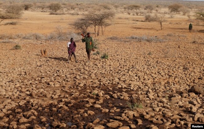 Armed Turkana tribesmen wait for cattle to get water from a borehole near Baragoy, Kenya, Feb. 14, 2017.