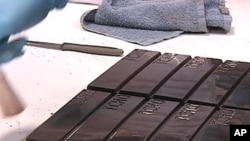A worker makes final preparations before a square of Tcho chocolates are separated and wrapped, Dec 2011