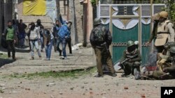 Des manifestants lancent des pierres sur des éléments des forces de sécurité indiennes devant un bureau de vote lors d'une élection partielle au Cachemire indien, le 9 avril 2017.