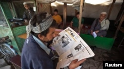 FILE - An Afghan man reads a newspaper at a tea shop in Kabul.