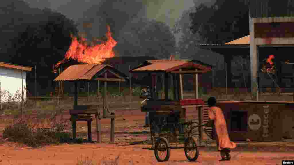 A girl pushes a hand cart past burning houses in Bossangoa, north of Bangui, Jan. 2, 2014.