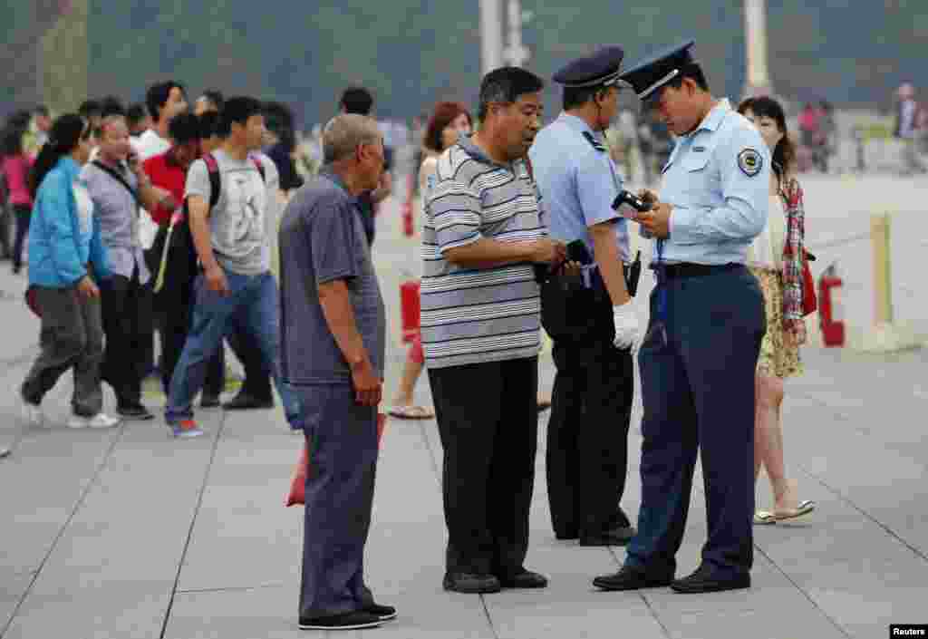 Seorang petugas keamanan memeriksa kartu identitas pengunjung di Alun-Alun Tiananmen di Beijing (4/6) dalam peringatan penumpasan militer terhadap gerakan pro-demokrasi di tempat tersebut. (Reuters/Kim Kyung-Hoon)