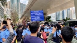 大批在場戒備的警員多次向西九法院大樓外排隊的市民高舉藍旗及紫旗，警告聚集的市民涉嫌非法集結，高呼的口號涉嫌違反國安法 (攝影：美國之音湯惠芸)