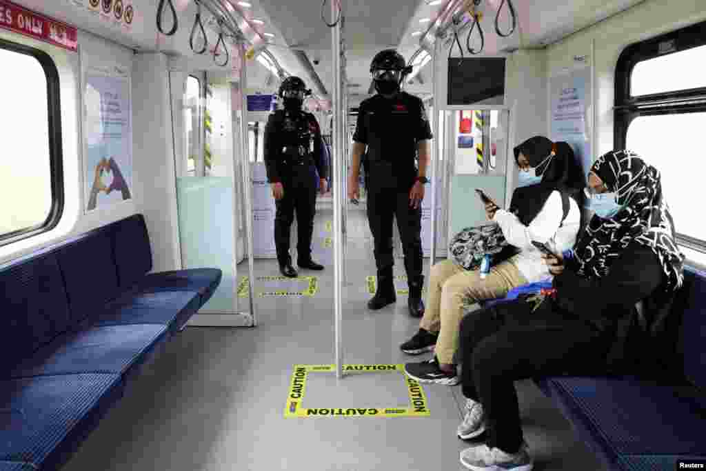 Auxiliary police officers wearing &#39;Smart Helmet&#39;, a portable thermoscanner that can measure the temperature of passengers at a distance, patrol inside a commuter train, in Kuala Lumpur, Malaysia.