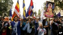 Villagers from Boeung Kak lake march through the main street, wearing a portrait of detained Yoam Bopha, Buddhism, poster and flags to mark the World Women's Day in Phnom Penh, Cambodia, Friday, March. 8, 2013. Bopha was arrested by local authorities after her protest over compensation for her loss of her house due to a new luxury housing development. The protesters demanded the release of Bopha. (AP Photo/Heng Sinith)